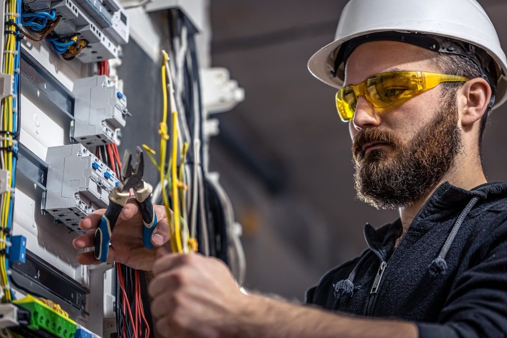 male-electrician-works-switchboard-with-electrical-connecting-cable-min